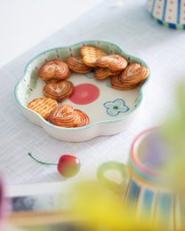 Ceramic flower-shaped platter with turquoise rim, blue floral patterns, pink center, serving dish.