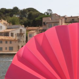  Red translucent hand fan with a pleated design, suitable for use in warm weather or as a decorative accessory.