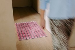 Pink checkered bath mat with textured stripe pattern, soft absorbent bathroom floor rug.