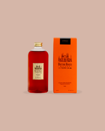  A tall, cylindrical glass bottle with a red liquid and a gold cap, accompanied by a smaller bottle with a similar design.