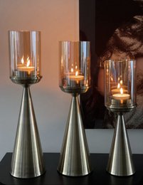  Tall, gold-colored glass candle holders with cylindrical glass inserts for tea lights.