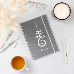 A gray spiral-bound daily planner with a mandala design, suitable for organizing daily tasks and schedules.