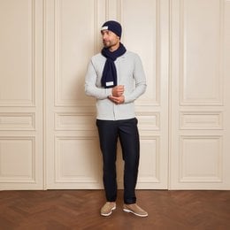 Navy blue knitted beanie with a white label patch, suitable for cold weather wear.