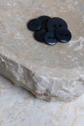 Deep charcoal black shiny buttons, round classic style, multiple sizes available for dress fastening.