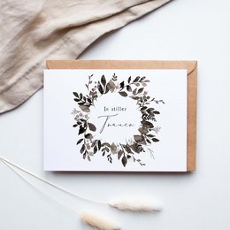 A folded card with a floral wreath design, suitable for expressing condolences.