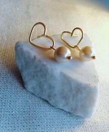 Gold heart-shaped earrings with white pearls. Elegant and feminine jewelry piece.