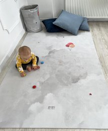A large, soft, gray rubber playmat with a cloud-like design and a red balloon floating in the sky. The mat appears to be suitable for children's play and relaxation.