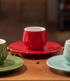Set of 4 red double-wall ceramic mugs with saucers, ideal for hot beverages. Features a modern, minimalist design with a vibrant red color.