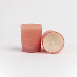 Hibiscus and mandarin scented candle in a round, tall glass container with a pink label.