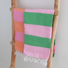 Colorful striped hammam cloth in pink, green, and orange with tasseled edges.
