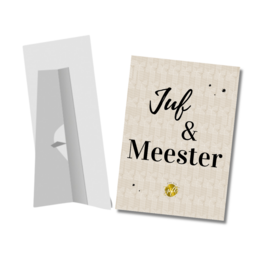 Presentation board with text "Juf & Meester" in a black frame with a yellow flower. The board appears to be made of cardboard or a similar material.