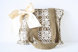 Crochet bag Odelia, a shoulder bag with a beige and brown floral pattern, featuring a large bow accent.