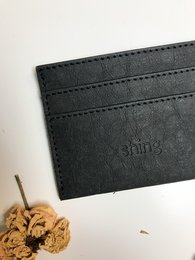 Black leather card holder with stitched edges and minimalist design.