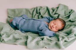 Soft, cozy mint green plaid baby blanket. Newborn baby sleeping peacefully wrapped in the warm, textured blanket.
