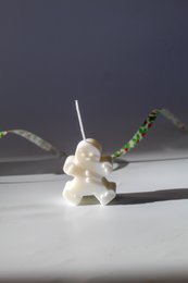 Tall, round, white soy wax candle with a decorative snowman figure on top.