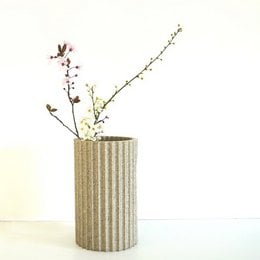 Tall, cylindrical vase in gray concrete-like material with delicate pink and purple flowers.