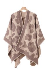  Cozy, oversized poncho in a neutral color palette with abstract geometric patterns. Made of soft, warm material suitable for layering in cool weather.