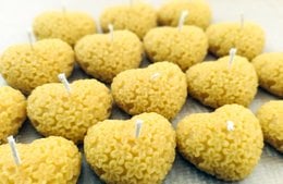 Heart-shaped beeswax tealight candles in a natural color. These candles have a warm, earthy tone and a textured, honeycomb-like surface.