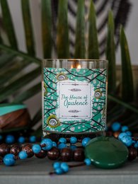 A round, tall, green-colored scented candle with a decorative label featuring a floral pattern.