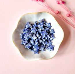  Small, irregularly shaped blue sodalite crystals in a white ceramic dish.