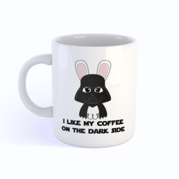 A white ceramic mug with a black and pink bunny design and the text "I like my coffee on the dark side". The mug features a playful, Star Wars-inspired design with a bunny character resembling Darth Vader.