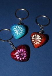 Colorful heart-shaped keychains made of soapstone, featuring floral designs in shades of blue, red, and pink.