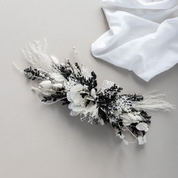 Dried flower arrangement with eucalyptus and dark accents. Tall, round vase with dried floral stems in neutral tones.