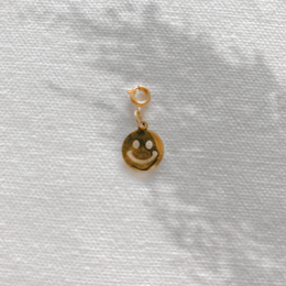 Cheerful smiley face pendant with gold tone metal frame.