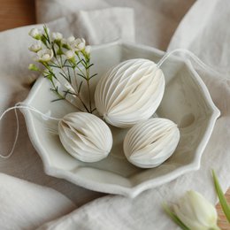  White paper Easter eggs in a decorative bowl with spring flowers.