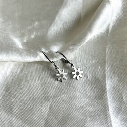 Silver hoop earrings with a floral charm. The earrings feature a round hoop design with a small flower-shaped charm attached.