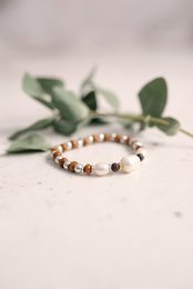 Beige and silver-toned beaded bracelet with a feather charm, suitable for casual or boho-chic style.