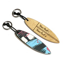 Personalized surfboard keychain made from recycled skateboards. Features colorful, unique design with a surfboard shape and text. Suitable for use as a keychain or accessory.
