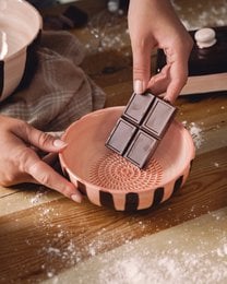 A round, multi-functional grater in a blue and white speckled pattern. The grater is available in small, medium, and large sizes, with and without packaging.