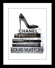 Black high-heel shoe on stack of fashion books, including Chanel and Louis Vuitton.