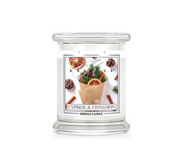  Medium-sized glass jar candle with a cypress and cinnamon scent, featuring a decorative label with pinecones and other natural elements.