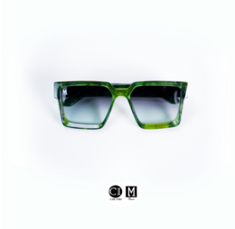 Oversized green sunglasses with a bold, square frame and gradient lenses. The sunglasses have the brand name "Monett Manifesto" printed on the side.