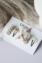  Set of 3 hair clips in varying sizes, featuring a neutral color palette and natural elements like feathers and pearls.