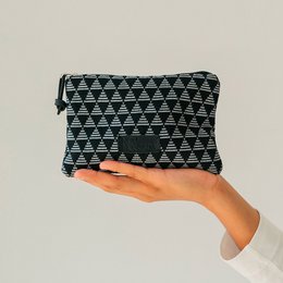 A small black and white patterned coin purse or wallet, featuring a triangular geometric design. The purse is being held in a person's hand, showcasing its compact and portable size.