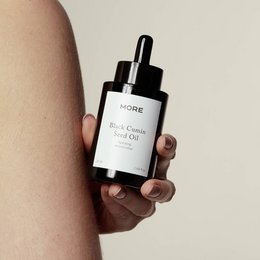 Black cumin seed oil, 100% organic and cold-pressed face oil in a glass bottle with dropper.