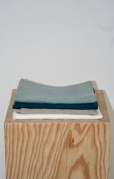 Linen placemats in natural, white with fringes, deep blue, wide stripes, and ocean blue colors. Rectangular shape with a textured linen material.