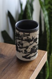 Black and white patterned ceramic mug with a cylindrical shape.