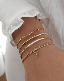 A set of delicate gold and rose gold bracelets with a natural, minimalist style. The bracelets feature a mix of chain, bead, and charm details for a chic, layered look.