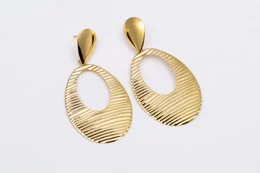 Gold-tone stainless steel statement earrings with a textured, oval-shaped design.