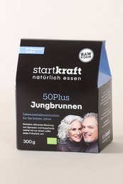 Organic superfood mix in a black and white package labeled "Starkraft Jungbrunnen". The product contains a blend of superfoods and is marketed as a "fountain of youth". The image also shows a bowl filled with the superfood mix, along with fresh fruits like apples and strawberries.