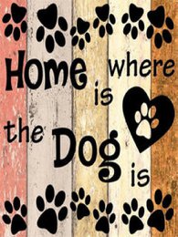  A colorful wooden sign with the text "Home is where the Dog is" and paw print designs. The sign features a rustic, distressed wood background with a warm color palette of orange, pink, and brown.