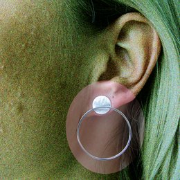 Circular statement earrings with a textured metal disc accent in a matte black metal frame.