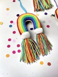 Colorful rainbow charm keychain with tassels, perfect for kids. Made of crochet and featuring a vibrant rainbow design.