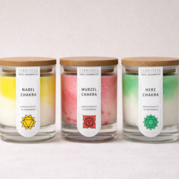  Three cylindrical soy candles with chakra symbols in yellow, pink, and green colors for meditation and relaxation.