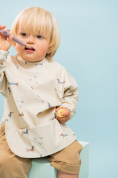 Long sleeve bib with various animal prints including teckels, kittens, dinosaurs, fruits, origami shapes, rainbows, safari animals, confetti, wild animals, and flying dogs. The bib is made of soft, comfortable material and features a variety of colorful, playful designs.