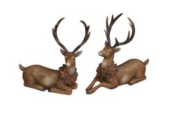  Two resting deer with large antlers. The deer appear to be made of a natural material, possibly wood or resin, and have a rustic, decorative appearance.